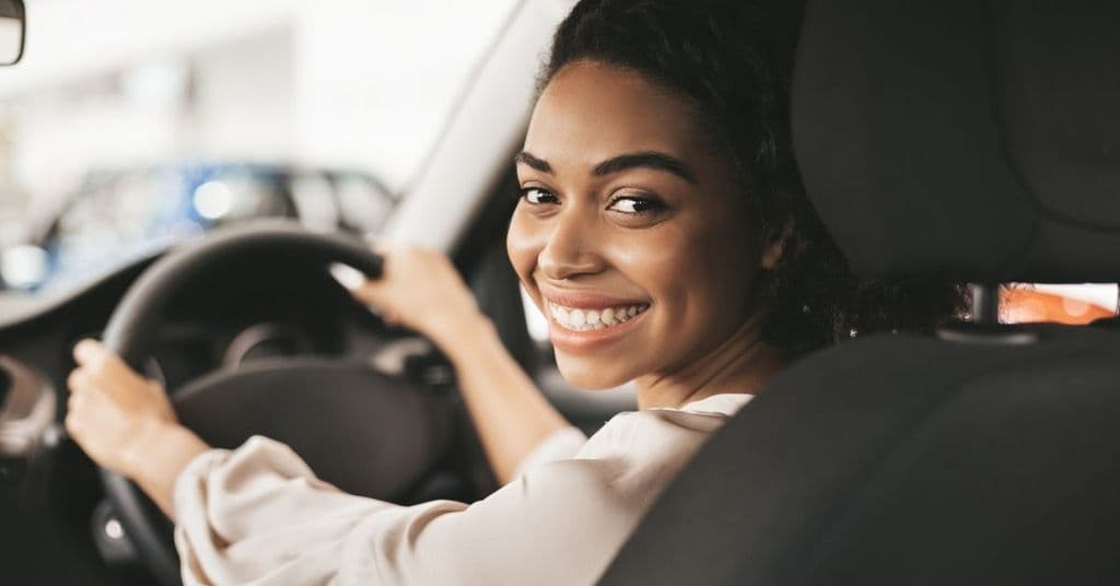 A driver smiling from the front seat of a car