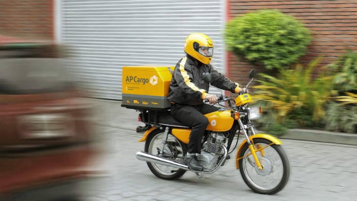 A courier riding a motorcycle to deliver a package